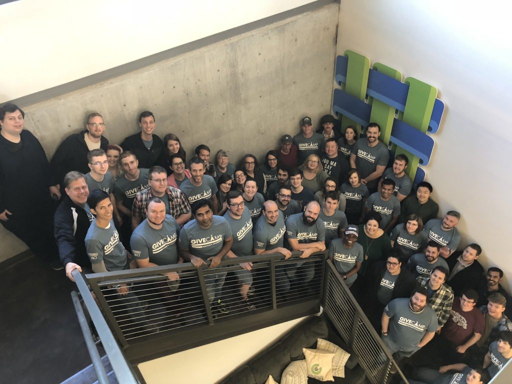 GiveCamp NWA volunteers and non-profit partners standing together in a large stairwell.